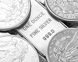 A one ounce silver bar and several one ounce silver coins